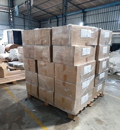 A shrink-wrapped pallet of labelled cartons being loaded at the factory dock
