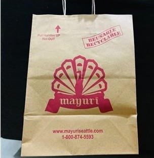 Kraft handle bag printed with the Mayuri peacock logo in pink